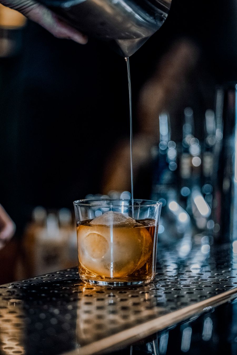 Un cocktail ambré versé sur un gros glaçon